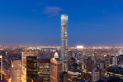 Illuminated cityscape against blue sky