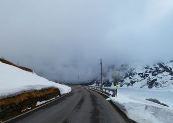 Road leading towards snow covered mountain against sky