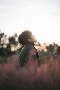 Side view of man standing on land against sky during sunset