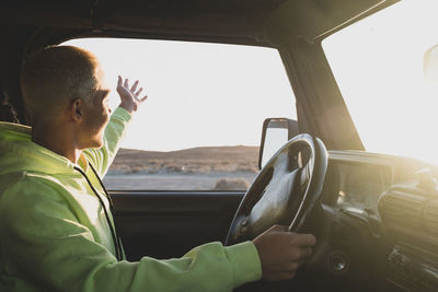 Side view of man looking away while driving car