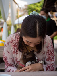 Midsection of woman holding cat sitting outdoors