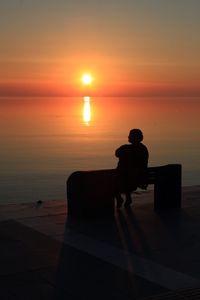 Silhouette people looking at sea during sunset