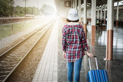 Rear view of man walking on railroad track