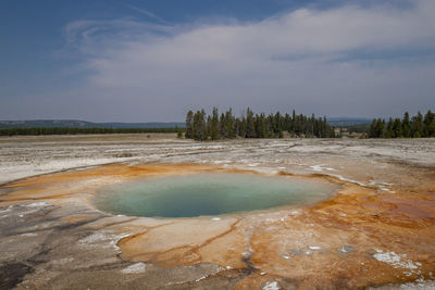 Hot spring at yellowstone national park against cloudy sky