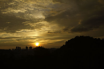 Silhouette landscape against dramatic sky during sunset