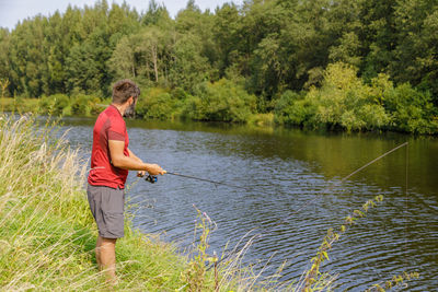 A man with a beard is fishing on the river. a fisherman with a fishing rod is fishing on the river