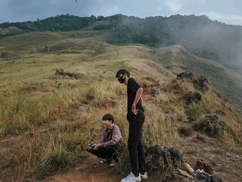 Young men on landscape against sky