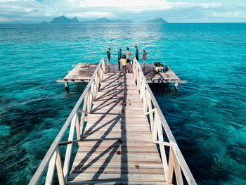 People on pier over sea against sky