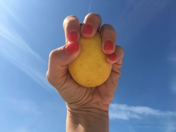 Close-up of hand holding ice cream against blue sky