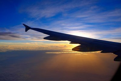 Airplane flying over sea against sky during sunset