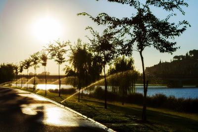 Road by river against clear sky during sunset