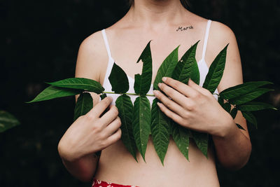 Midsection of woman holding leaves in forest