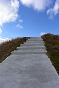 Road leading towards landscape against sky