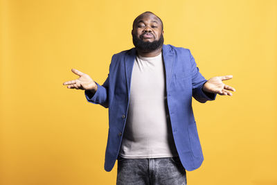 Portrait of young man standing against blue background