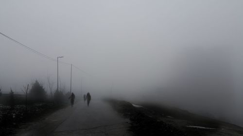 Rear view of people walking on snow covered landscape