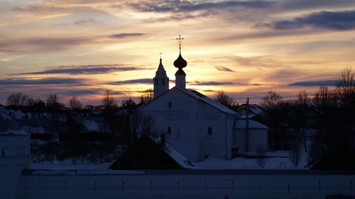 Church by building against sky during sunset