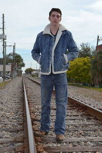 Portrait of young man standing on railroad track