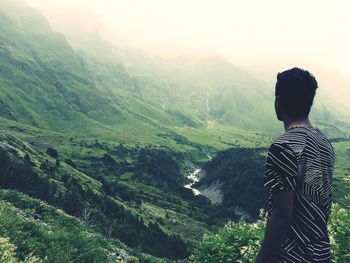 Rear view of woman standing on mountain in forest