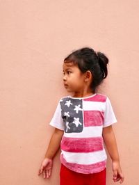 Girl looking away while standing against wall