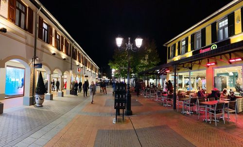 People on street amidst buildings at night