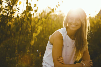 Smiling young woman on field during sunny day