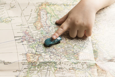 Cropped hand of child holding toy car on map