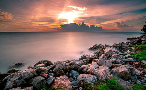 Rocks on stone beach at sunset. beautiful landscape of calm sea. tropical sea at dusk.