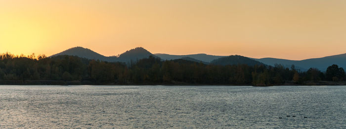 Scenic view of lake and mountains against orange sky