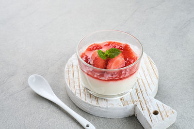 Sweet vanilla silky pudding dessert with strawberry sauce, sliced fresh strawberries and mint 