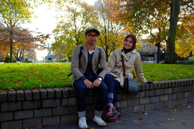 Full length portrait of friends sitting on park