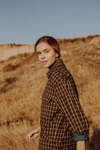 Portrait of young woman standing by plants against sky