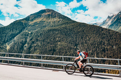 Man riding bicycle on mountain against sky