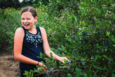 Girl harvesting berries while standing by trees