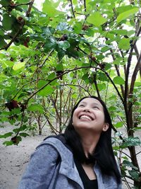 Cheerful young woman looking at fruit trees at farm