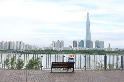 Rear view of man sitting on bench in city