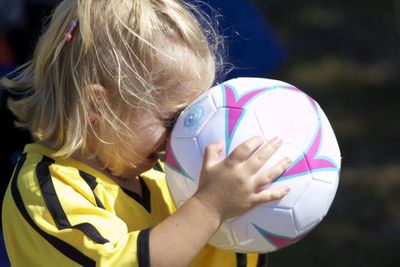 Close-up of girl holding soccer ball while crying outdoors