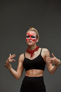 Portrait of young woman with arms crossed standing against black background