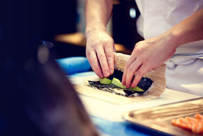 Midsection of chef preparing sushi in restaurant