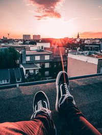 Low section of man with cityscape against sky during sunset