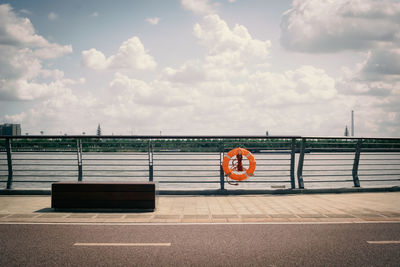 Graffiti on railing by sea against sky