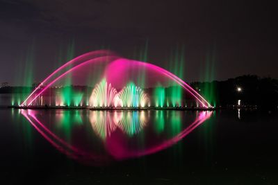 Reflection of illuminated lights in lake against sky at night