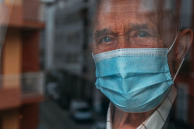 Portrait of man wearing mask looking through window