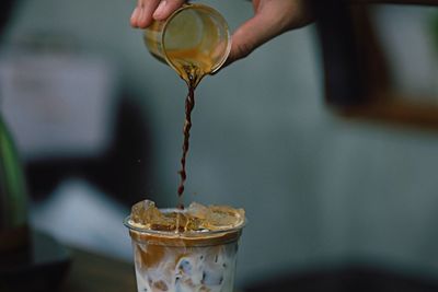 Cropped hand pouring coffee in glass