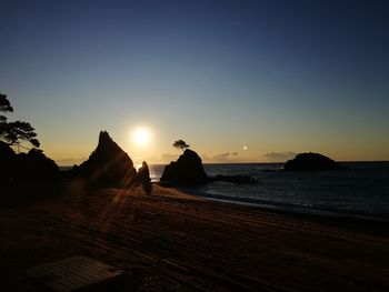 Silhouette people on beach against sky during sunset