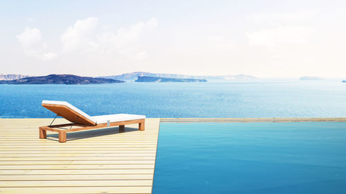 Chaise longue by sea against sky