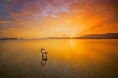 Scenic view of lake against dramatic sky during sunset