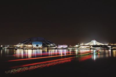 River by illuminated singapore national stadium against clear sky at night