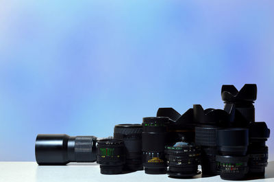 Close-up of camera and lenses on table against blue background