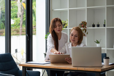 Woman using phone while sitting on table at home