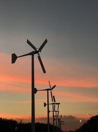 Low angle view of silhouette windmills against sky during sunset